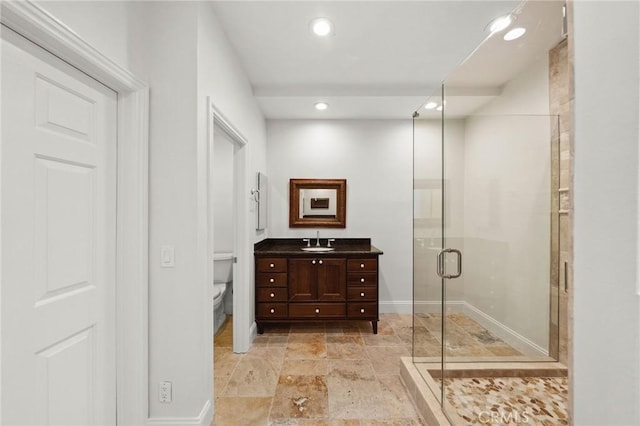 bathroom with a stall shower, stone tile floors, toilet, vanity, and recessed lighting