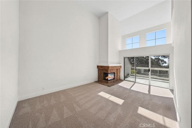 unfurnished living room with carpet, a multi sided fireplace, a towering ceiling, and baseboards