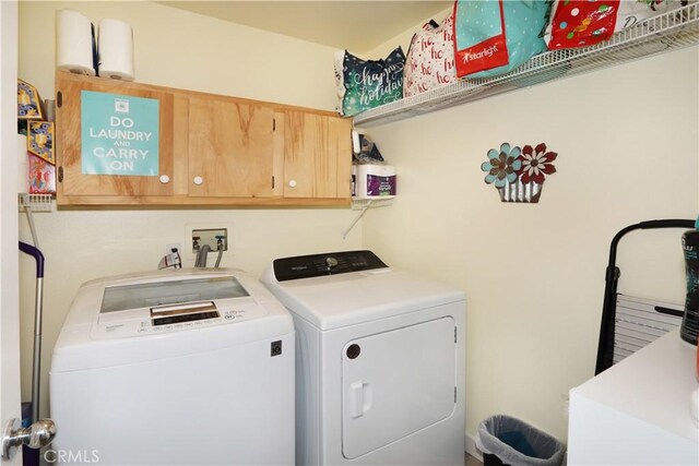 clothes washing area featuring washing machine and dryer and cabinets