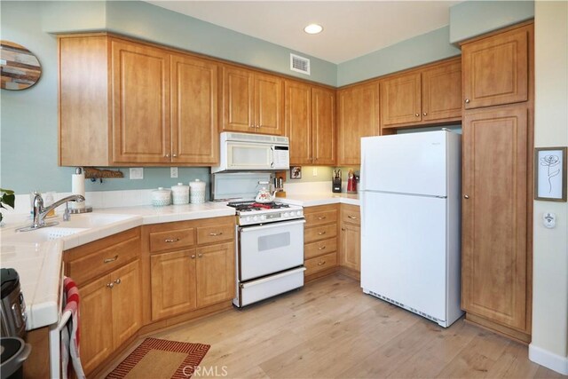 kitchen with sink, white appliances, and light wood-type flooring