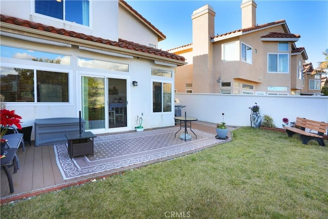 rear view of property with a yard, a chimney, fence, and stucco siding