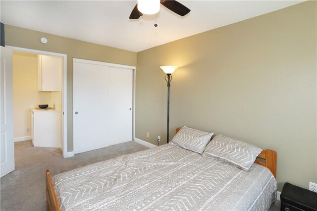 bedroom with ceiling fan, light colored carpet, and a closet