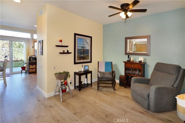 sitting room featuring light wood-style floors, baseboards, visible vents, and a ceiling fan