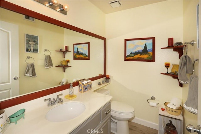 bathroom featuring toilet, baseboards, visible vents, and vanity