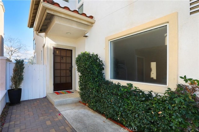 property entrance with fence and stucco siding