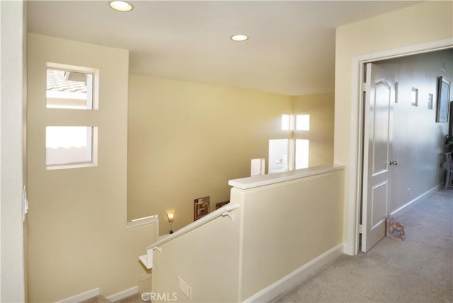 corridor featuring carpet, recessed lighting, baseboards, and an upstairs landing