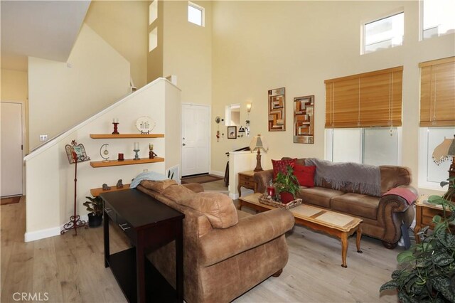 living room featuring a towering ceiling and light hardwood / wood-style floors