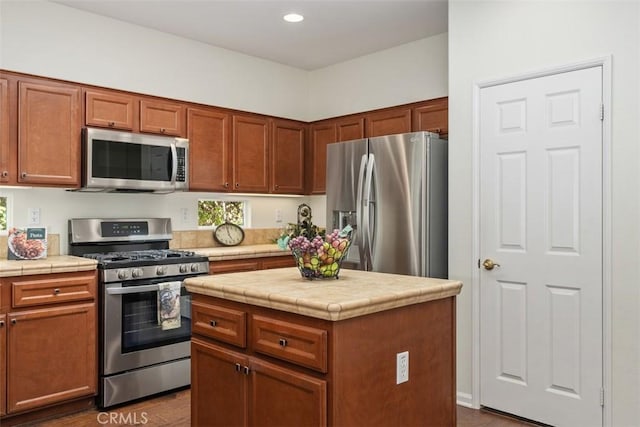 kitchen with brown cabinets, tile counters, stainless steel appliances, and recessed lighting