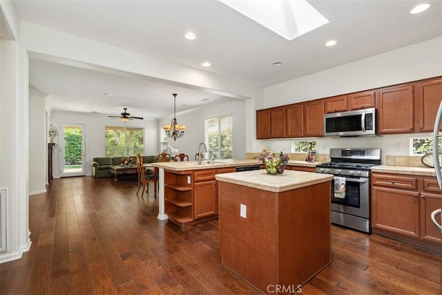 kitchen featuring a healthy amount of sunlight, appliances with stainless steel finishes, open floor plan, and dark wood-type flooring