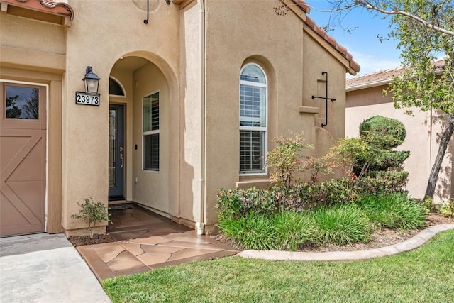 view of exterior entry featuring a tile roof and stucco siding