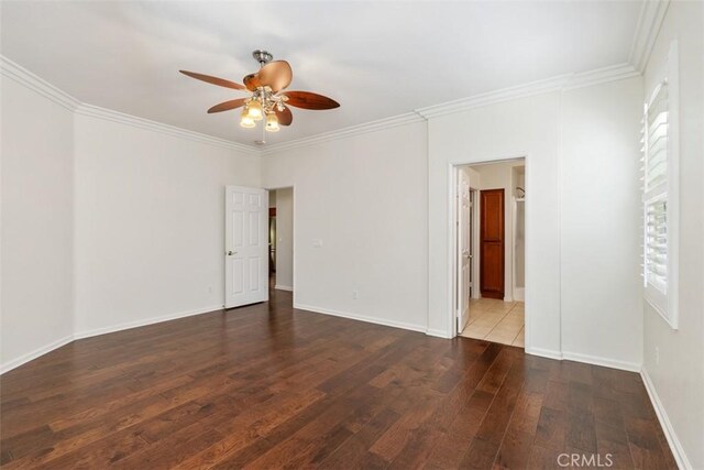 empty room featuring ornamental molding, hardwood / wood-style flooring, and baseboards