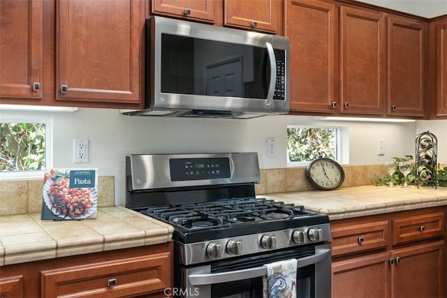 kitchen featuring tile countertops, stainless steel appliances, and brown cabinets