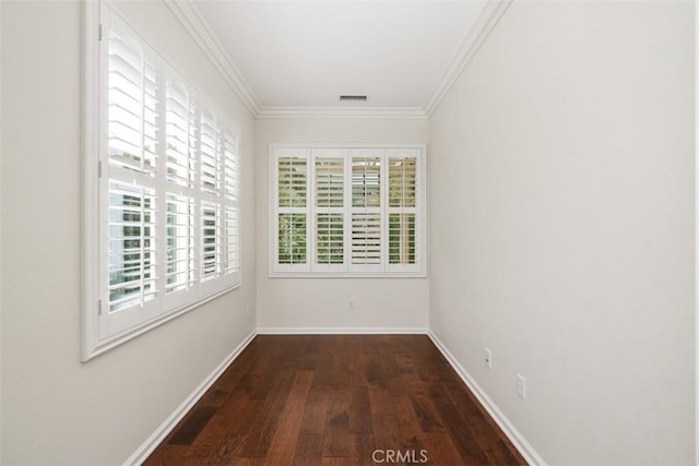 unfurnished room featuring baseboards, wood finished floors, visible vents, and crown molding