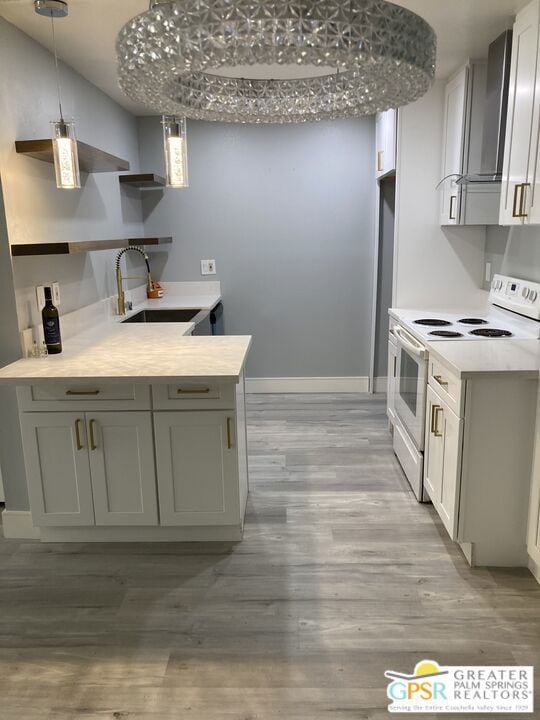 kitchen with wall chimney exhaust hood, white electric range, light hardwood / wood-style floors, and sink