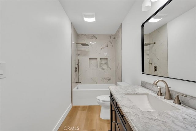 full bathroom featuring vanity, hardwood / wood-style flooring, tiled shower / bath combo, and toilet