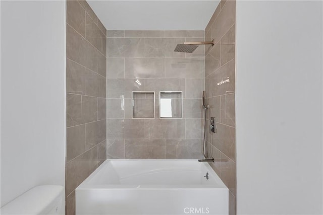 bathroom featuring tiled shower / bath and toilet