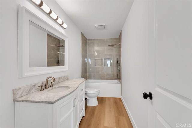 full bathroom with vanity, hardwood / wood-style floors, tiled shower / bath combo, and toilet