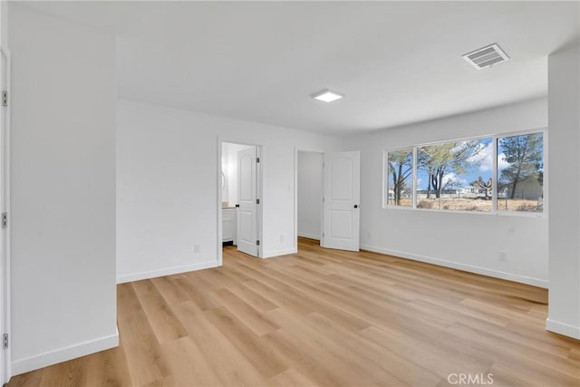 unfurnished bedroom with ensuite bathroom and light wood-type flooring