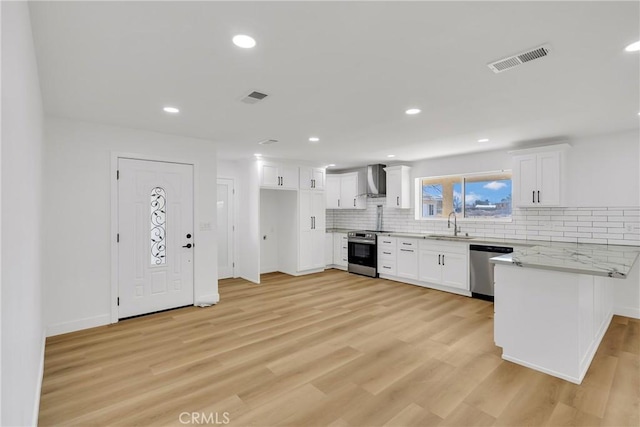 kitchen with sink, appliances with stainless steel finishes, white cabinetry, light stone countertops, and light hardwood / wood-style floors