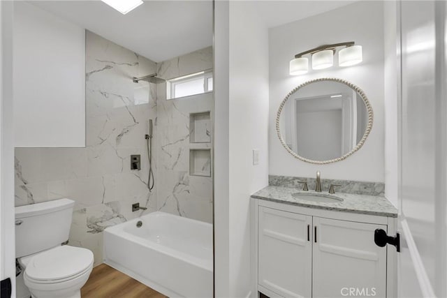 full bathroom with toilet, tiled shower / bath, tile walls, vanity, and hardwood / wood-style flooring