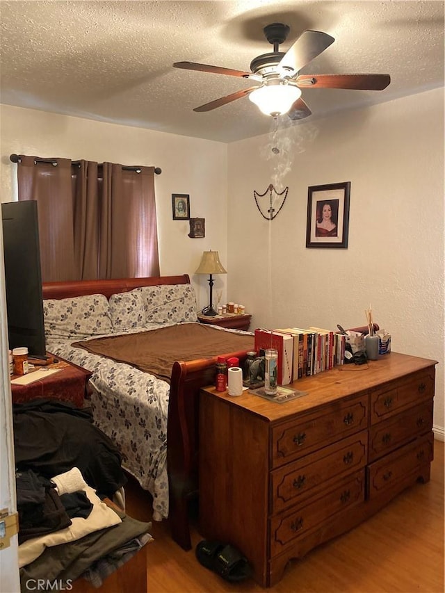 bedroom featuring ceiling fan, a textured ceiling, and light wood-type flooring