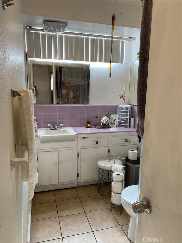 bathroom featuring tasteful backsplash, tile patterned floors, toilet, and vanity