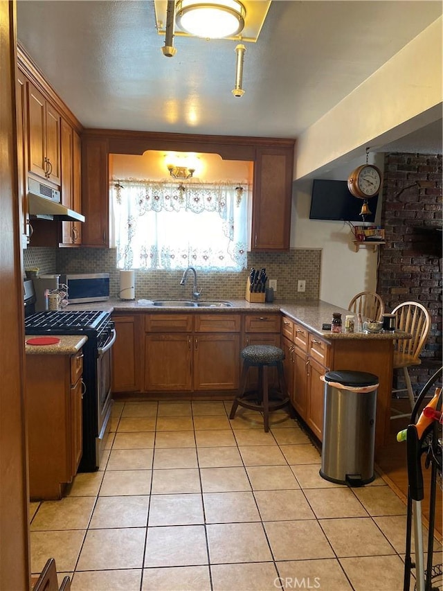 kitchen with sink, stainless steel gas stove, light tile patterned floors, dark stone counters, and backsplash