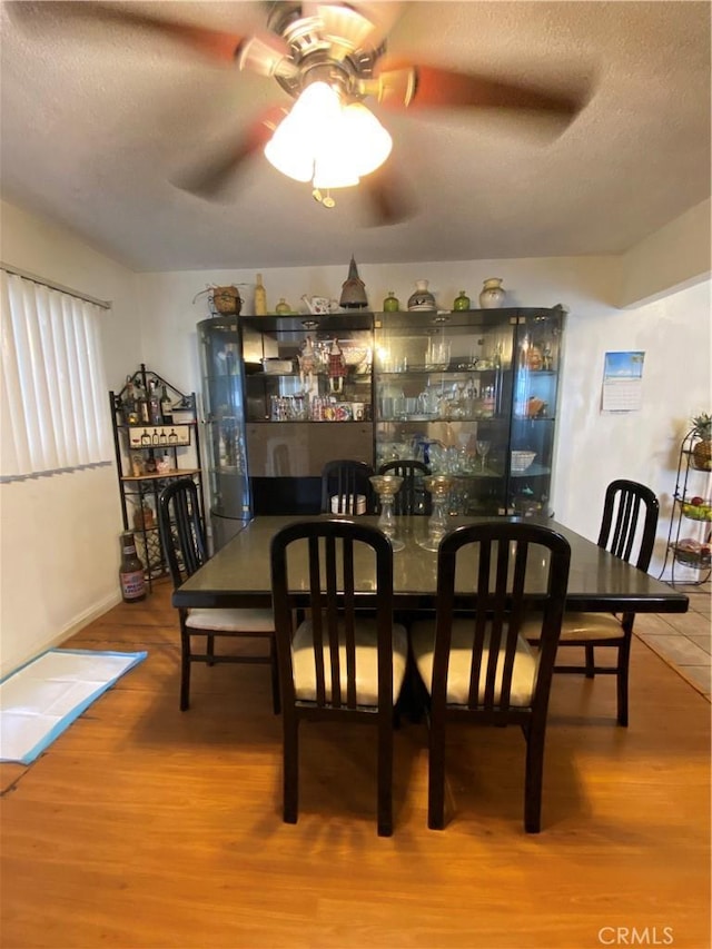 dining room featuring hardwood / wood-style flooring, ceiling fan, and a textured ceiling