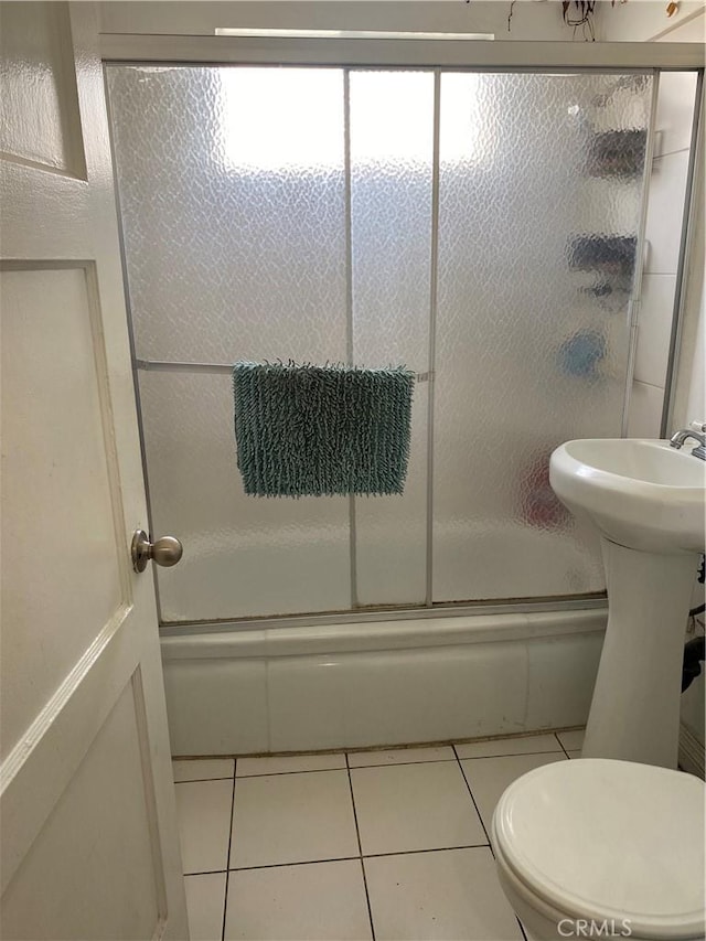 bathroom featuring tile patterned floors, toilet, and combined bath / shower with glass door