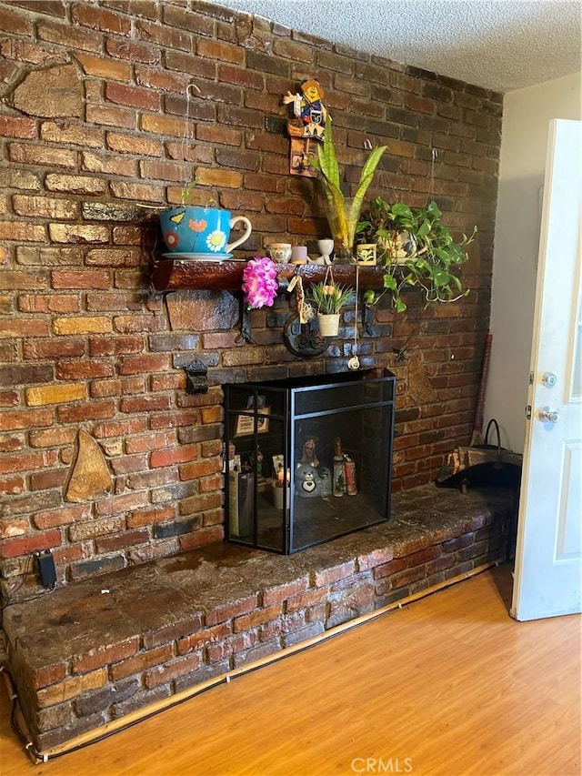 interior details with hardwood / wood-style floors, a brick fireplace, and a textured ceiling