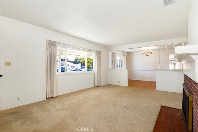 unfurnished living room featuring a brick fireplace, light colored carpet, a notable chandelier, and visible vents