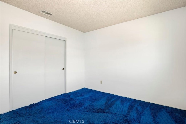 unfurnished bedroom featuring carpet, a closet, visible vents, and a textured ceiling