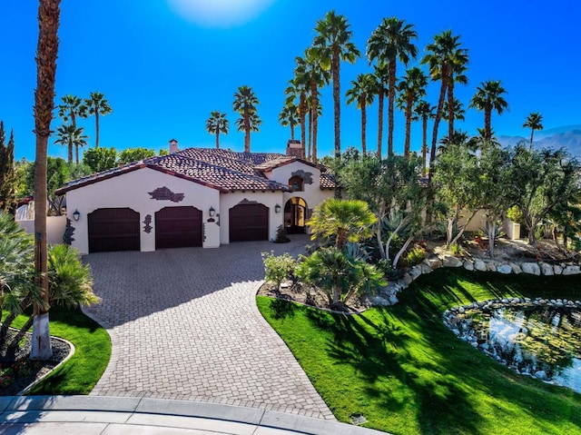 mediterranean / spanish home featuring a garage and a front lawn