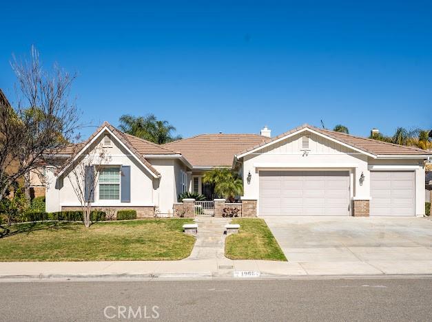 view of front of property featuring driveway, an attached garage, a front lawn, and a tiled roof