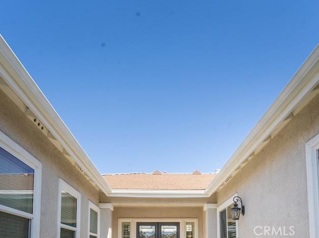 details with gutters, french doors, and stucco siding