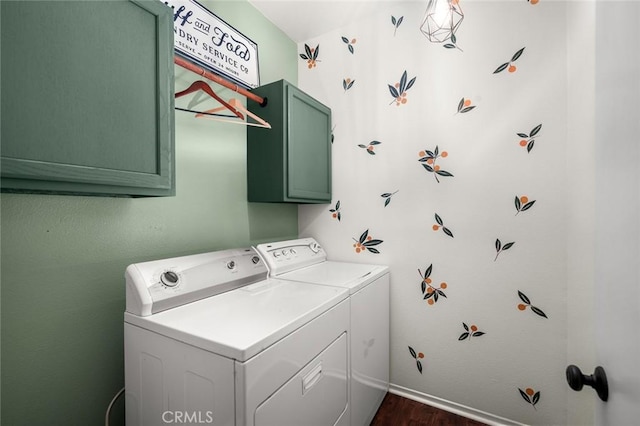 clothes washing area featuring cabinets, dark wood-type flooring, and washer and clothes dryer