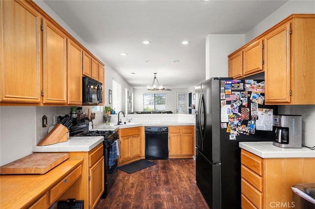 kitchen with black appliances, sink, dark hardwood / wood-style flooring, hanging light fixtures, and kitchen peninsula