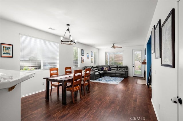 dining space with ceiling fan with notable chandelier and dark hardwood / wood-style floors