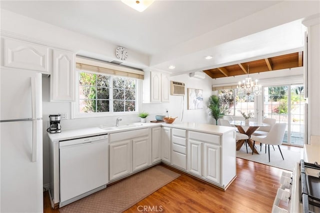 kitchen with white cabinetry, white appliances, a healthy amount of sunlight, and kitchen peninsula