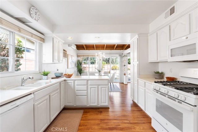 kitchen featuring white appliances, a wealth of natural light, kitchen peninsula, and white cabinets