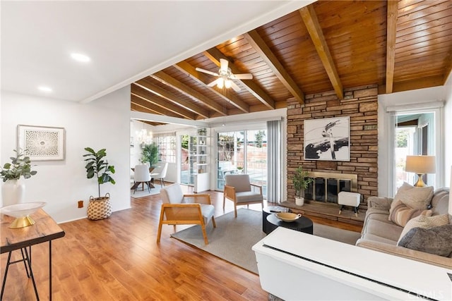 living room featuring wood ceiling, hardwood / wood-style flooring, ceiling fan, beam ceiling, and a fireplace