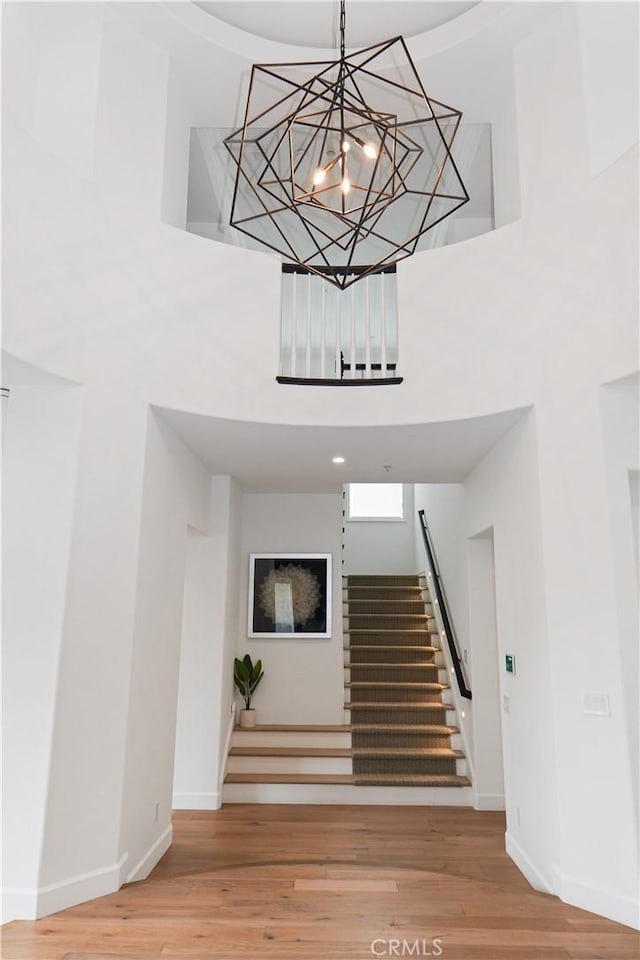 stairs featuring a high ceiling, baseboards, and wood finished floors