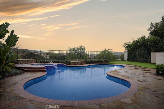 pool at dusk with a patio area and an in ground hot tub