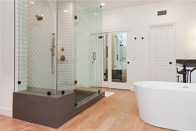 bathroom with hardwood / wood-style floors and separate shower and tub