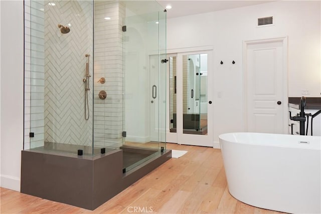 full bathroom featuring wood finished floors, visible vents, recessed lighting, a stall shower, and a freestanding bath