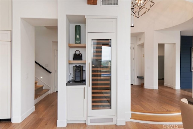 kitchen with light hardwood / wood-style flooring, beverage cooler, and white cabinets