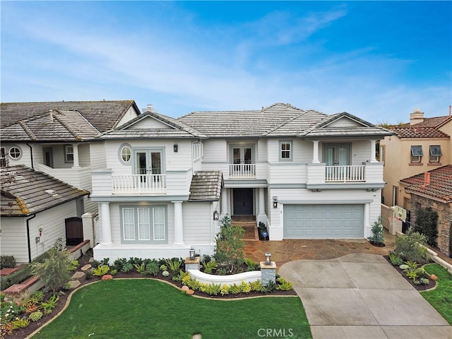 view of front of house with french doors, a balcony, a garage, and a front lawn