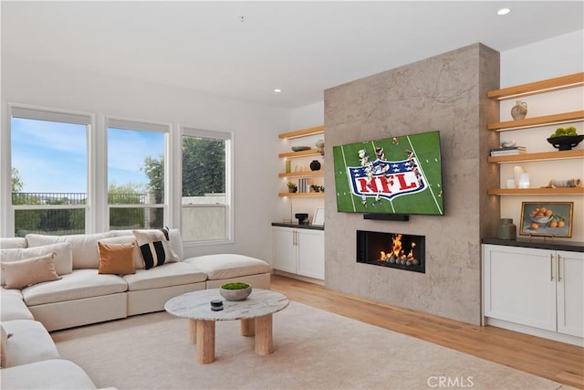 living room featuring a tiled fireplace and light hardwood / wood-style floors