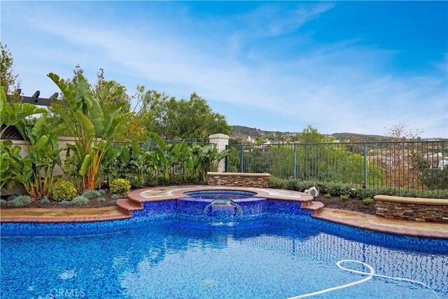 view of pool with a fenced in pool, an in ground hot tub, and fence