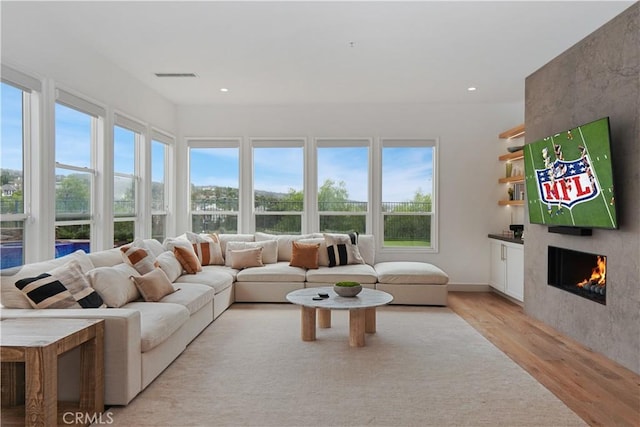 living room with a healthy amount of sunlight, a large fireplace, and light wood-type flooring